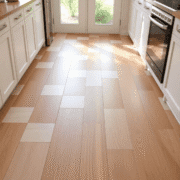 A bright kitchen floor with sections of ceramic tiles, wood, vinyl, and laminate flooring illuminated by natural light, highlighting clean textures.