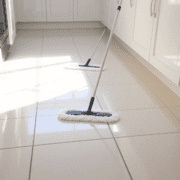 Bright kitchen floor with shiny ceramic tiles being mopped, soft natural light highlighting the clean surface and subtle grout lines.