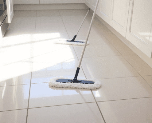 Bright kitchen floor with shiny ceramic tiles being mopped, soft natural light highlighting the clean surface and subtle grout lines.