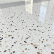 Close-up of a polished terrazzo floor with colorful marble and glass chips in a smooth, shiny surface under soft natural light.
