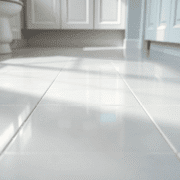 Close-up of clean, shiny ceramic and porcelain tiles with bright white grout lines in a well-lit bathroom or kitchen floor.