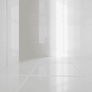 Close-up of glossy white porcelain tiles reflecting soft light, highlighting their smooth, shiny surface and elegant texture in a modern bathroom.