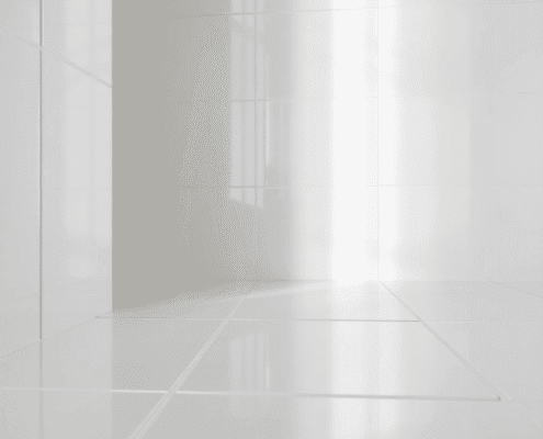 Close-up of glossy white porcelain tiles reflecting soft light, highlighting their smooth, shiny surface and elegant texture in a modern bathroom.