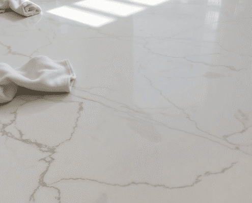 Close-up of polished marble floor with natural veins, sunlight highlighting its shine, and a soft cloth with pH-neutral cleaner nearby.