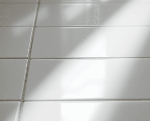 Close-up of shiny ceramic tiles with mist lifting to reveal clean grout lines, highlighted by soft natural light on smooth tile surfaces.